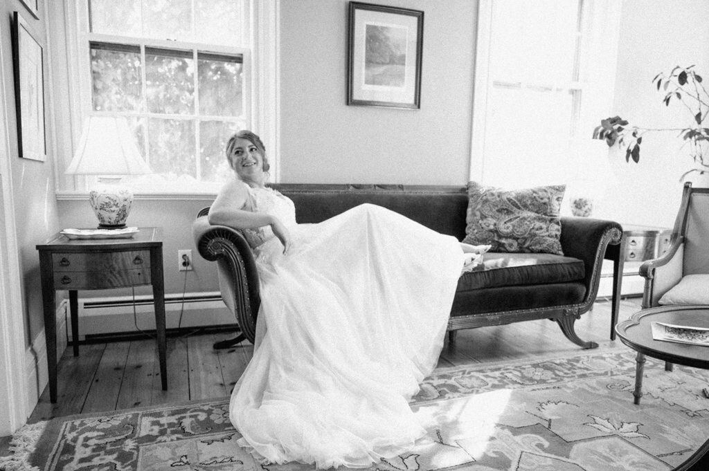 Bride sitting on couch while getting ready for wedding in Groton, MA