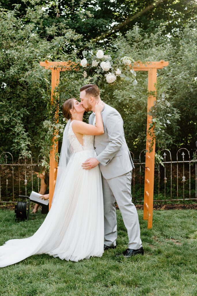 Outdoor garden ceremony at The Herb Lyceum with bride and groom first kiss 