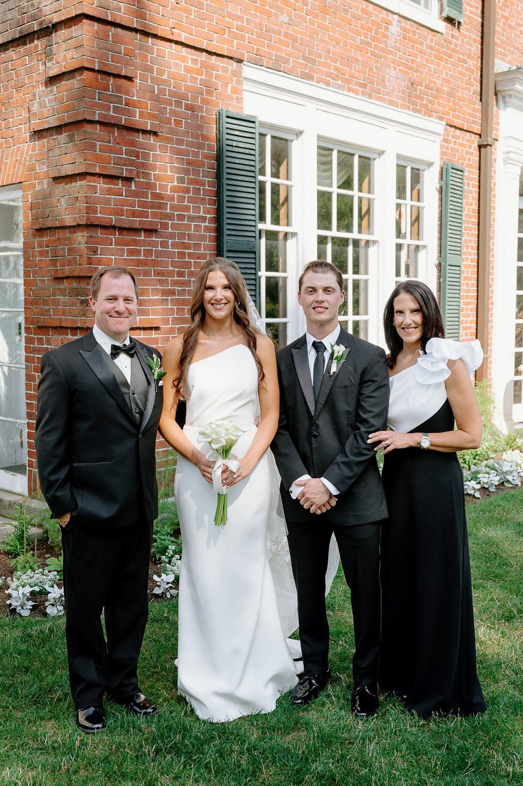 newlyweds with their family behind a brick house, planned as part of their wedding timeline.