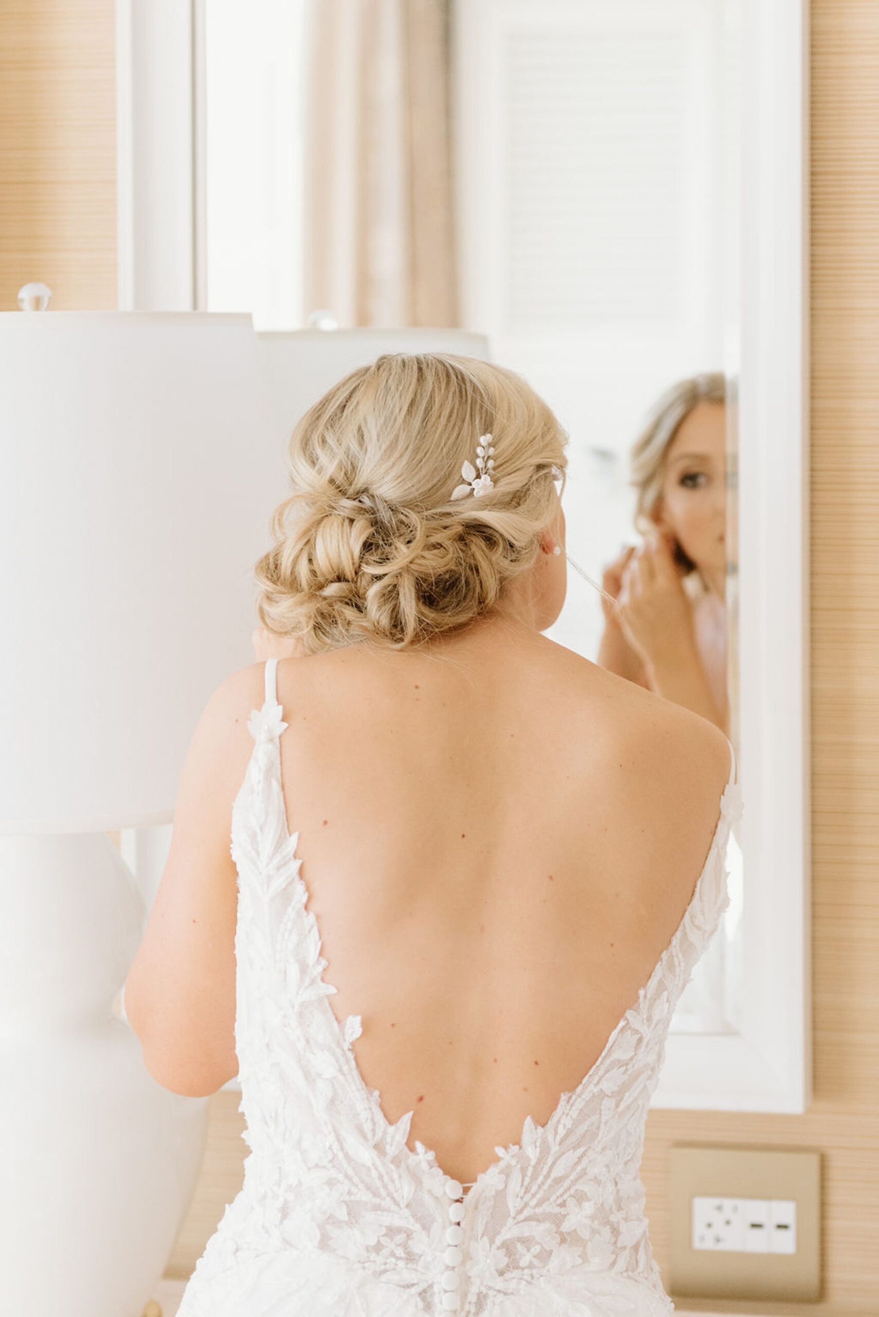 The bride putting on an earring in her hotel room at Encore Boston Harbor, one of the best small wedding venues in MA. 