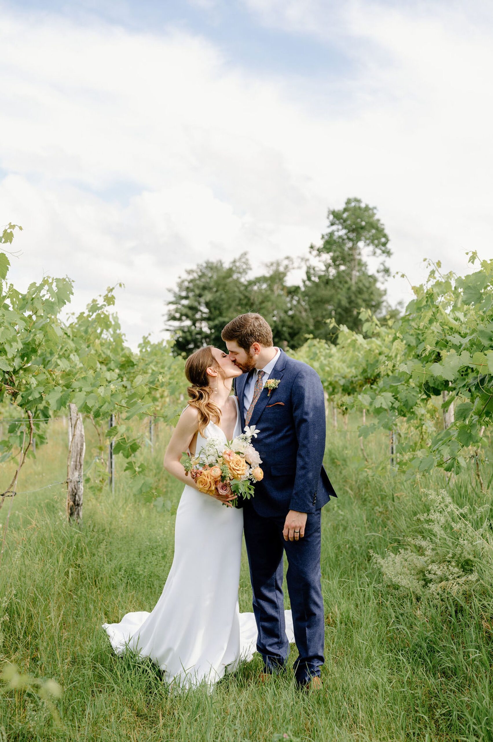 newlyweds kissing in the middle of a vineyard. 