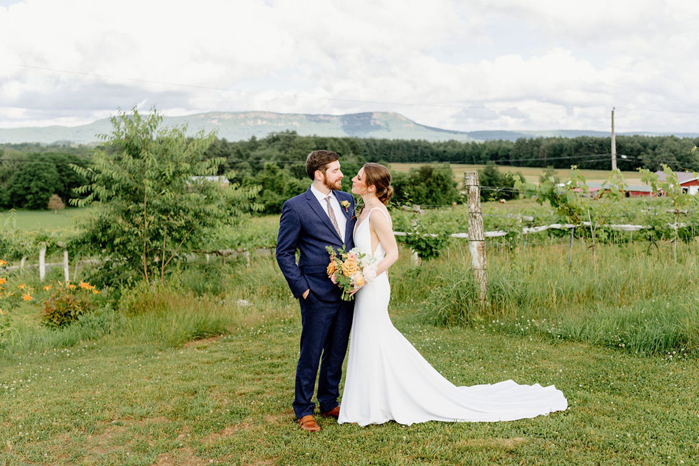 newlyweds looking lovingly into each other's eyes with rolling fields around them. 