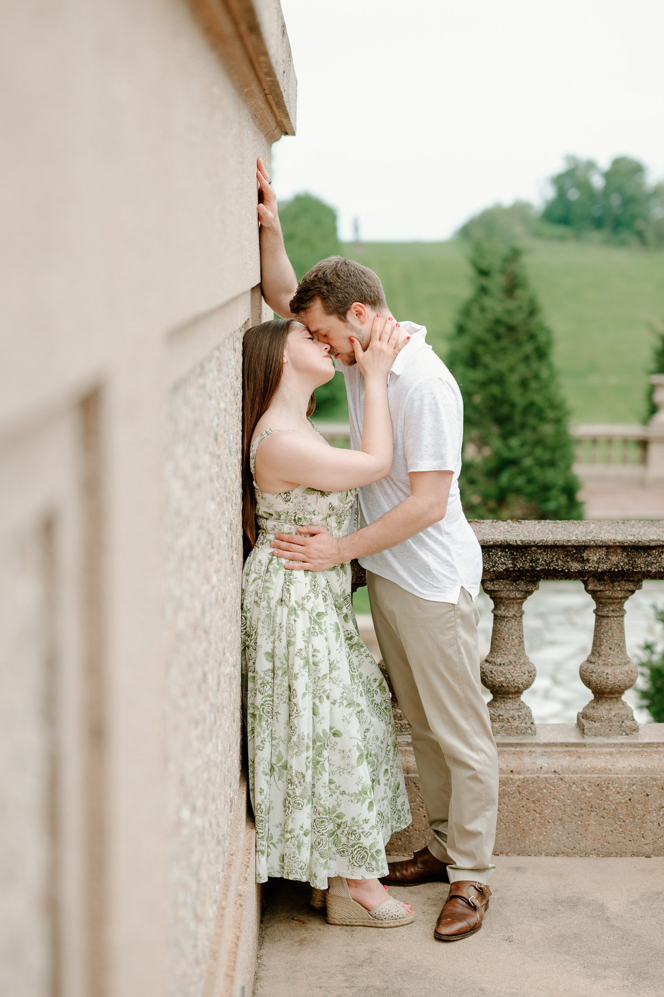 a couple kissing against the side of a building. 