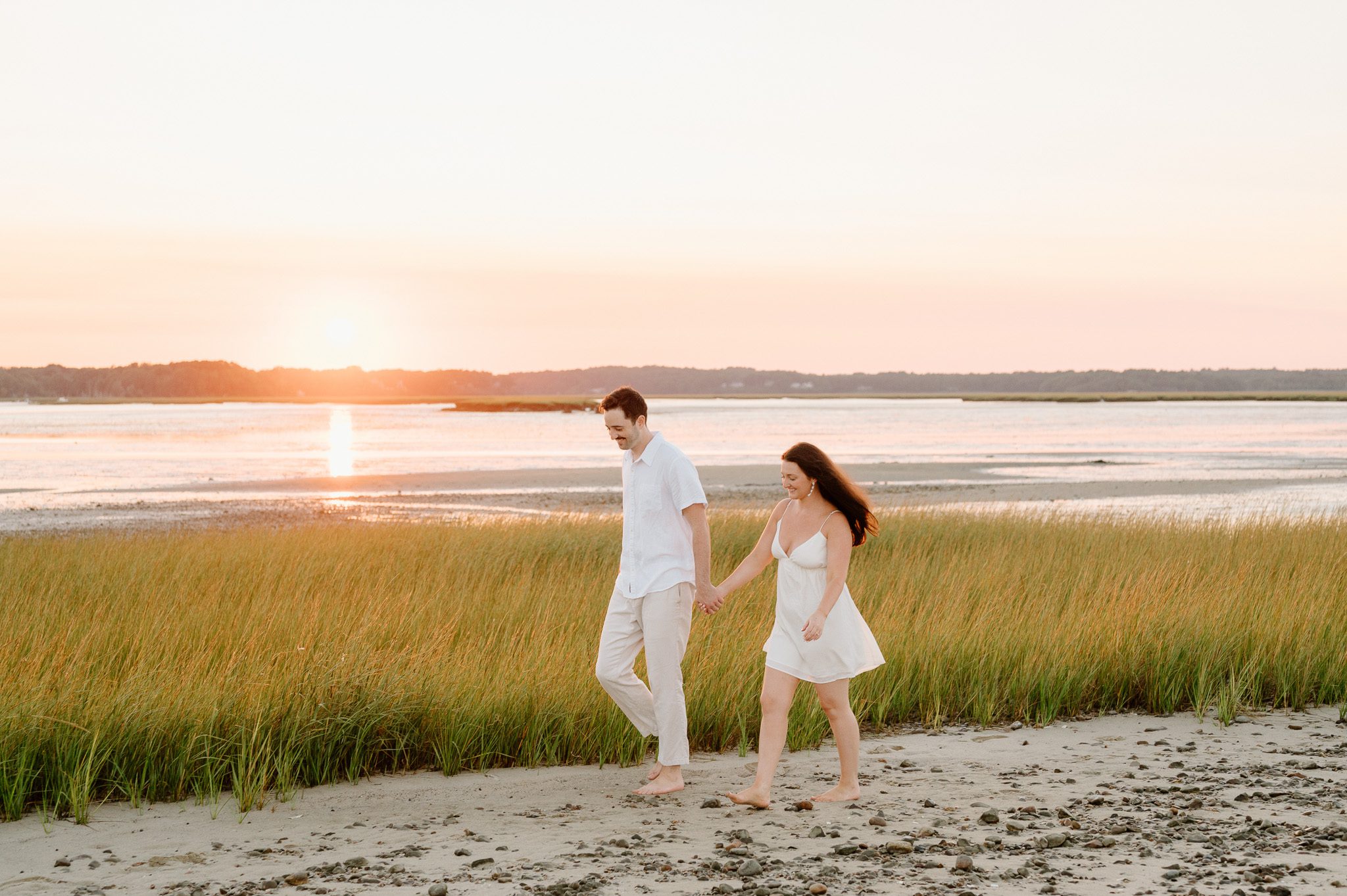 newlyweds holding hands walking on the sand. 