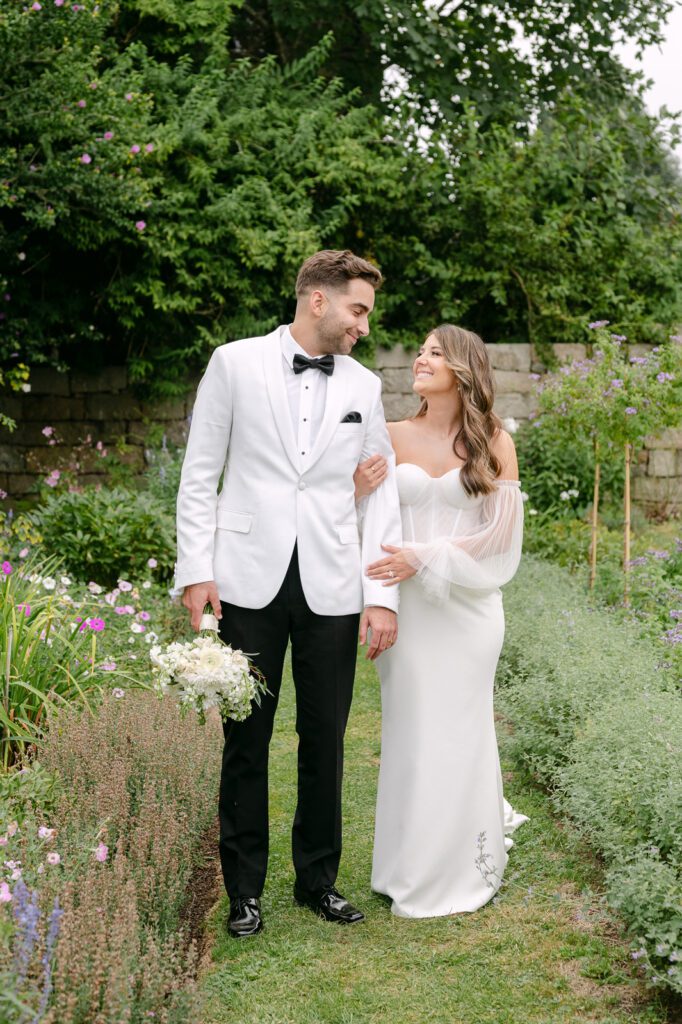 newlywed posing and smiling in a garden.