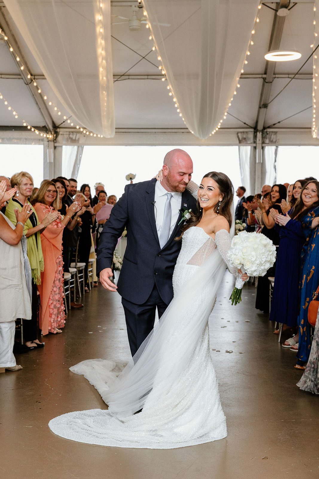 newlyweds holding their ceremony under a tent, happy because they had a plan in case it rains on their wedding day. 