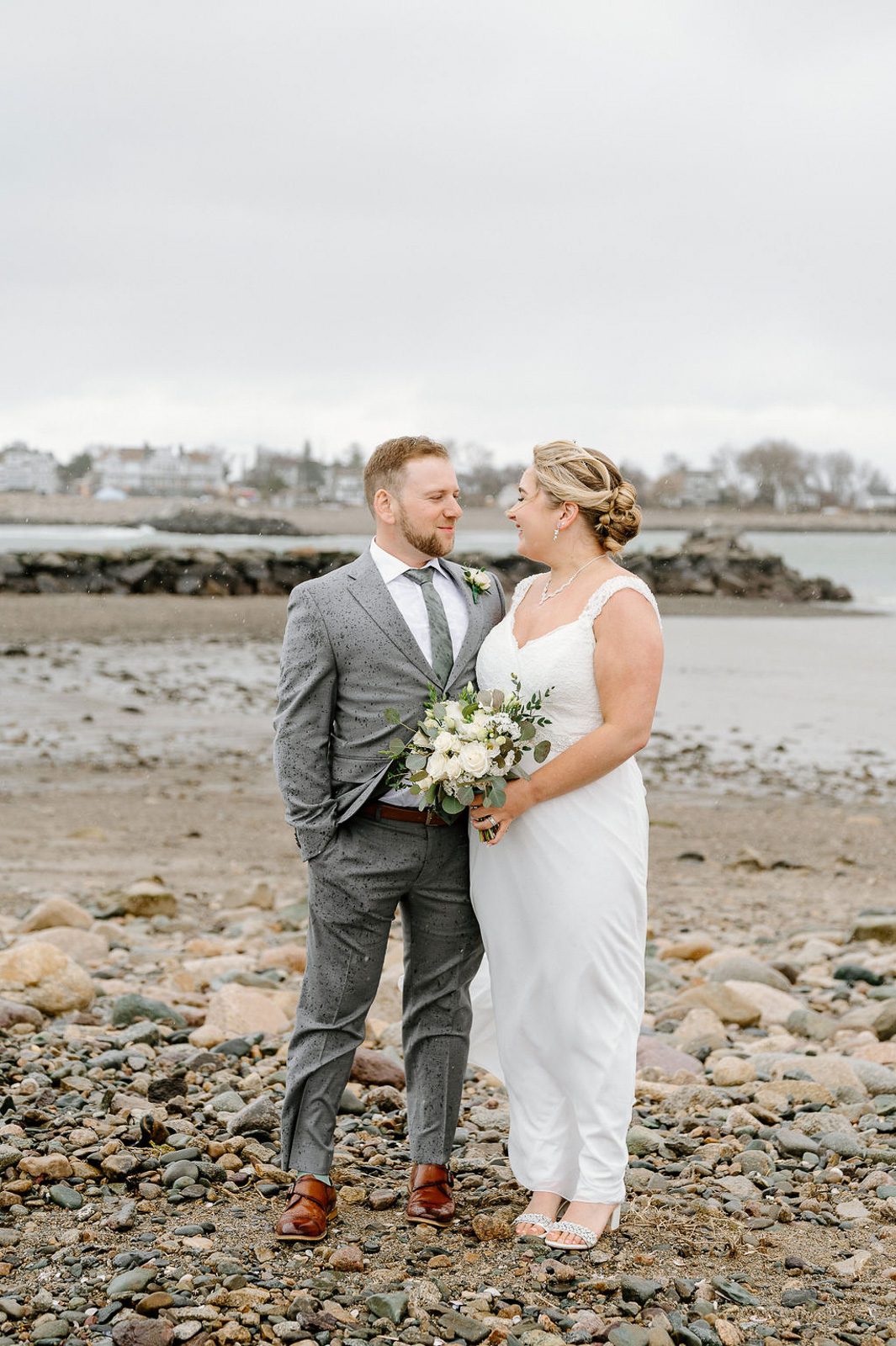 newlyweds next to each other standing in the rain. 