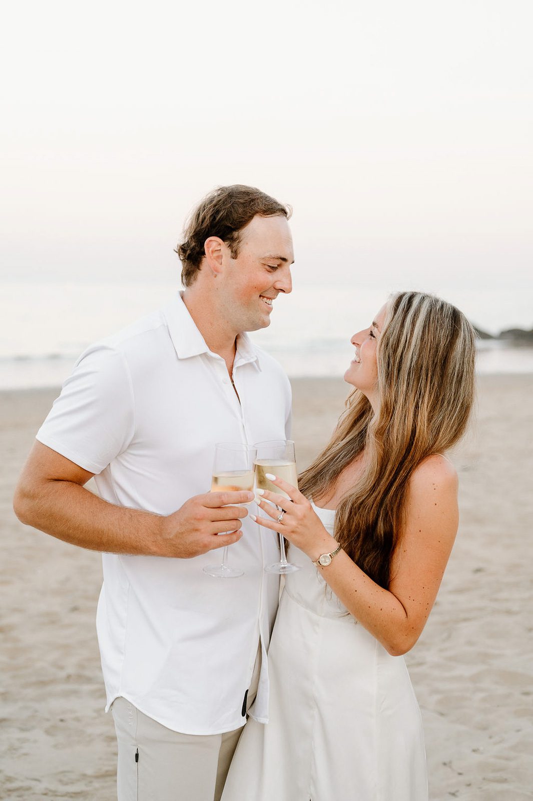 couple cheersing on the beach after their engagement.