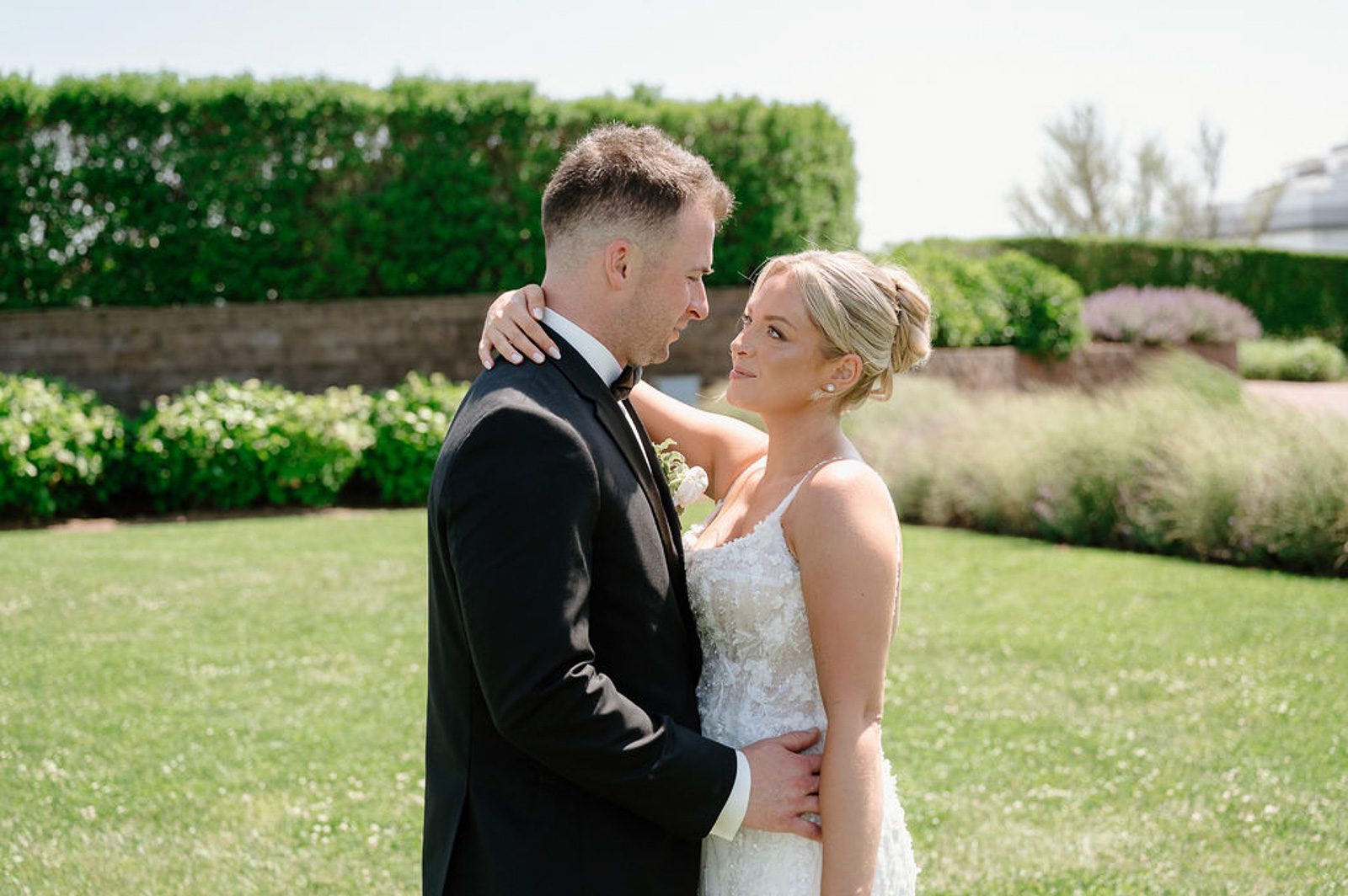 newlyweds admiring each other on a grassy lawn, beautifully captured by their last minute wedding photographer. 