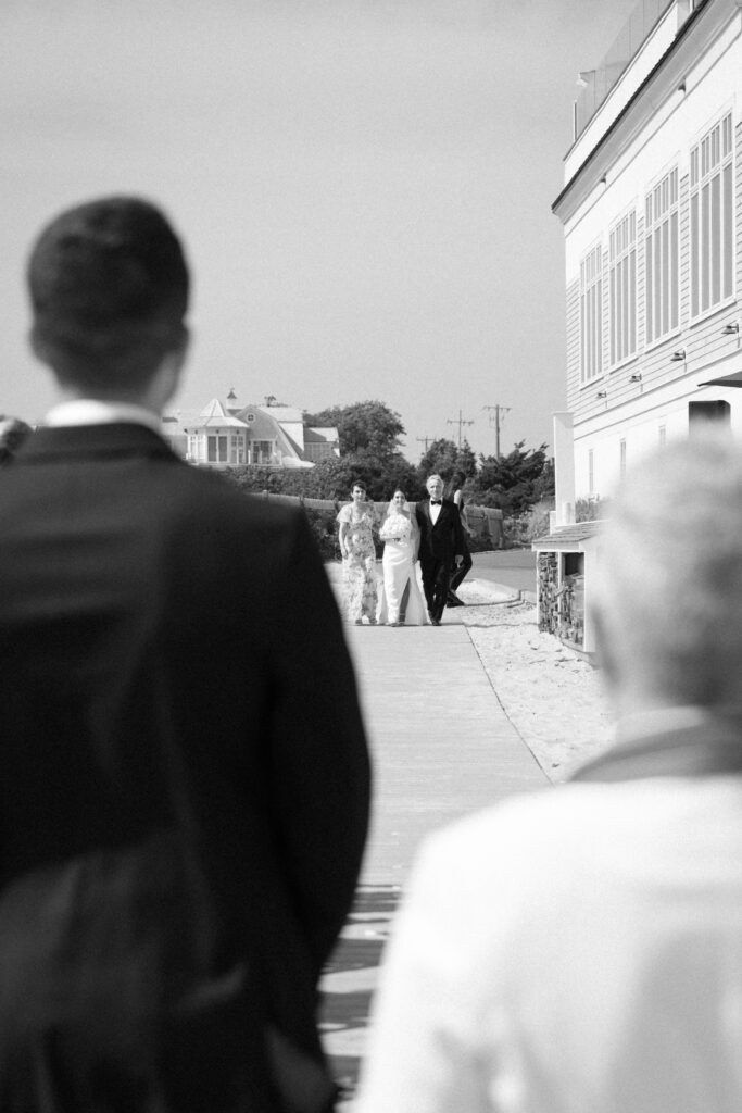 Beach ceremony at Wychmere Beach Club on Cape Cod with guests overlooking the ocean.