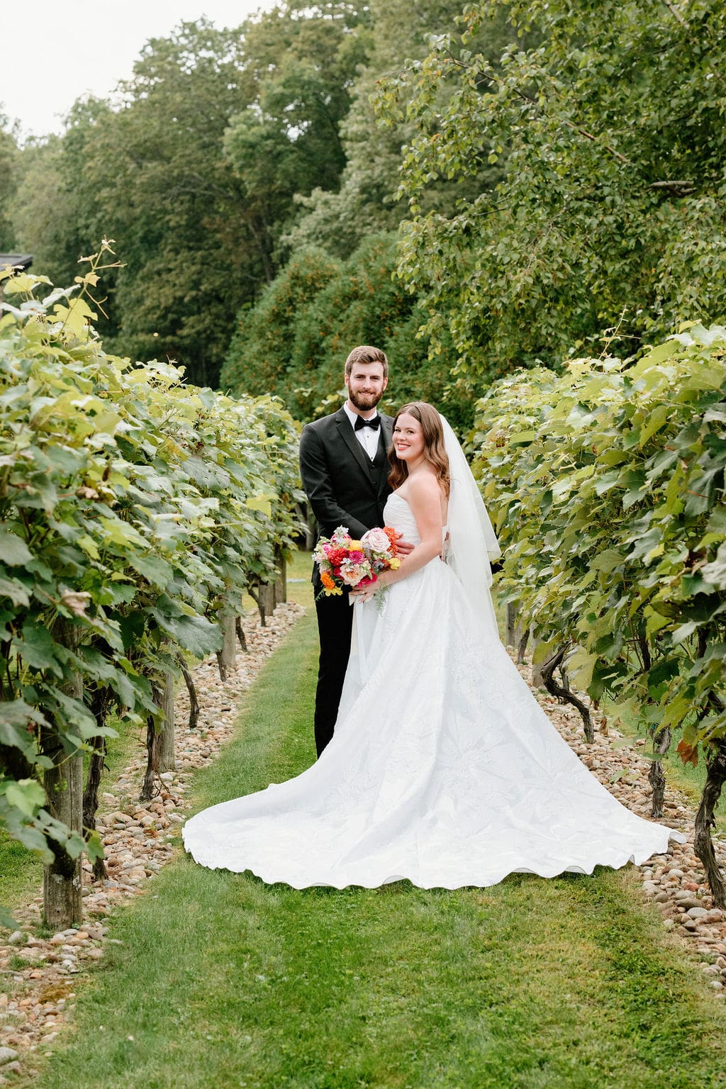 Couple walking through vineyard rows at Birch Wood Vineyards wedding