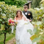 Couple walking through vineyard rows at Birch Wood Vineyards wedding