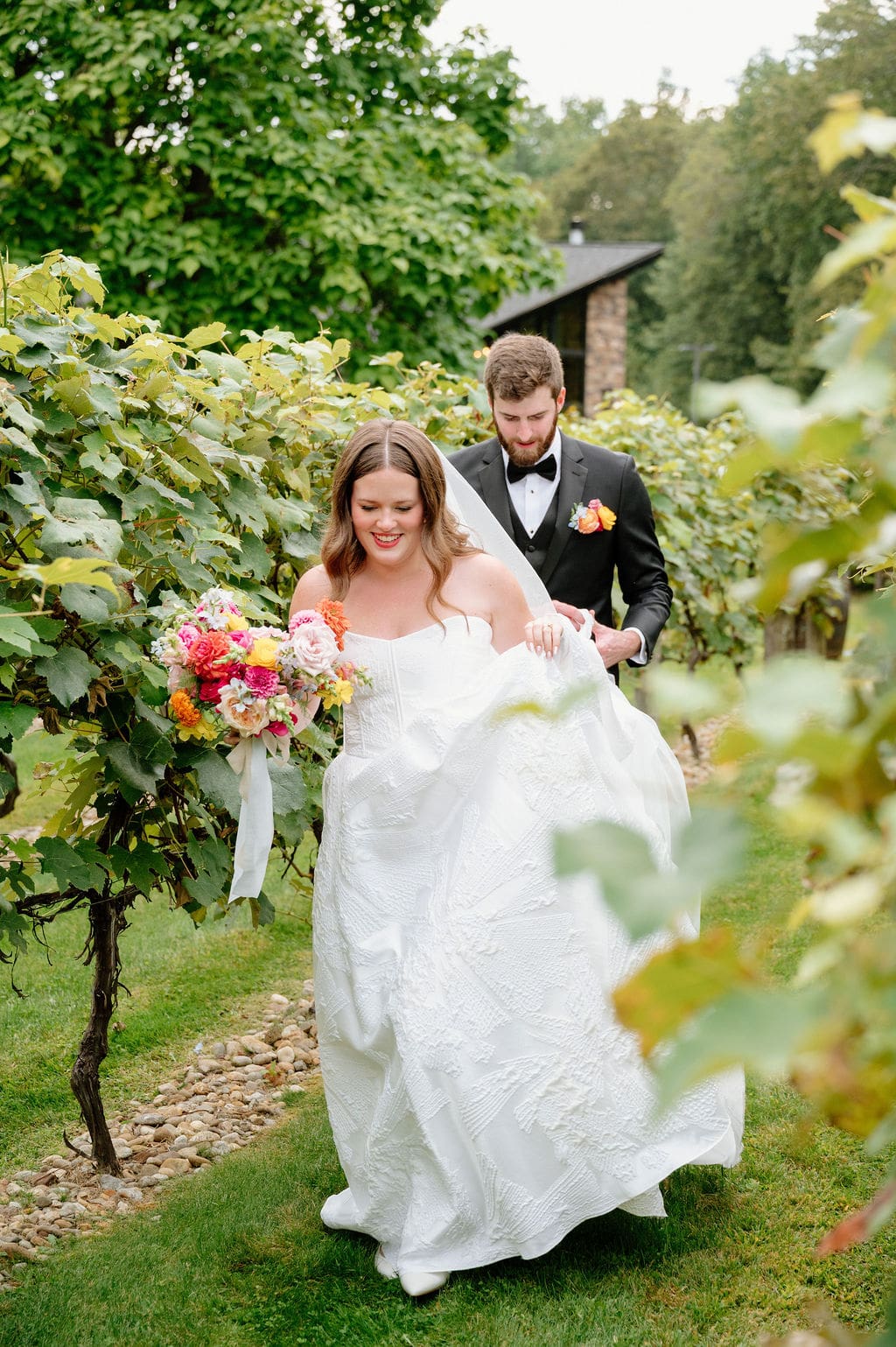 Couple walking through vineyard rows at Birch Wood Vineyards wedding